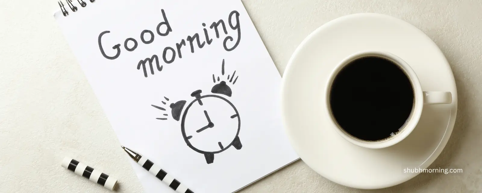 Good morning written on a notepad with a drawn alarm clock, beside black coffee