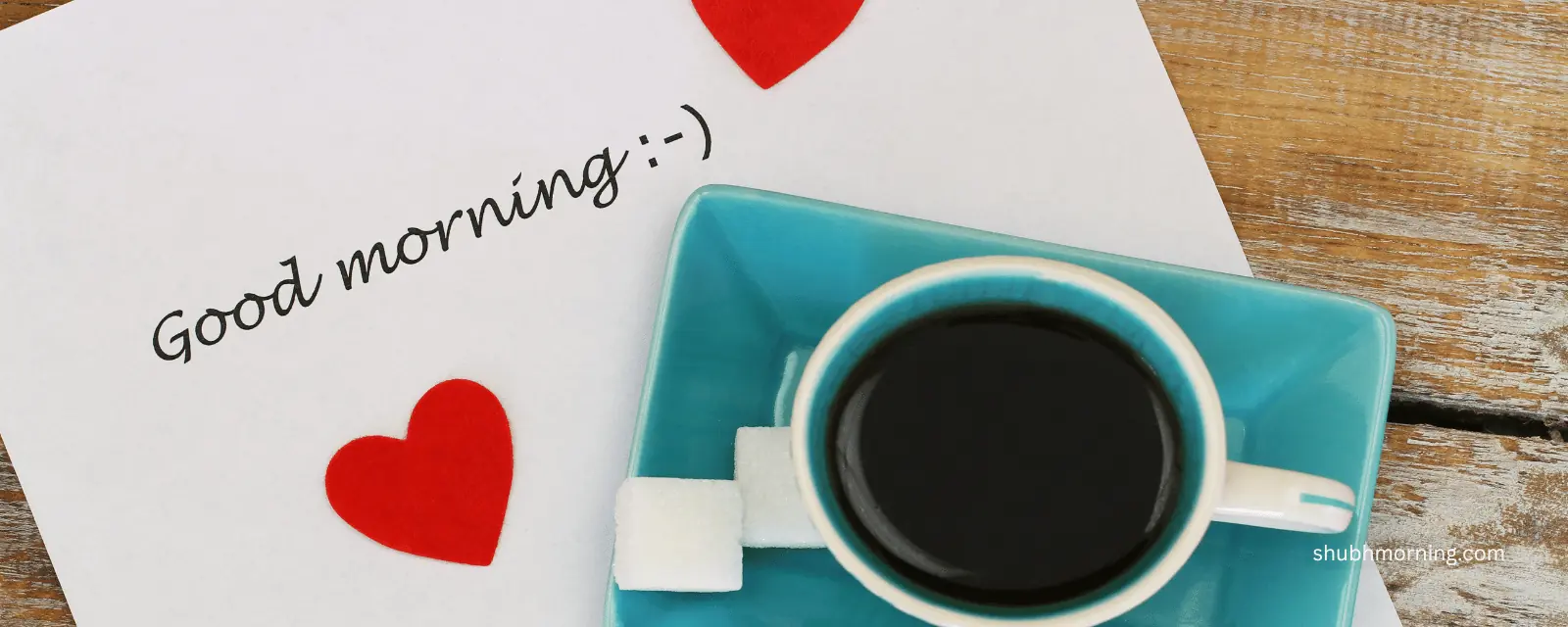 Good morning note with red paper hearts beside a teal cup of black coffee